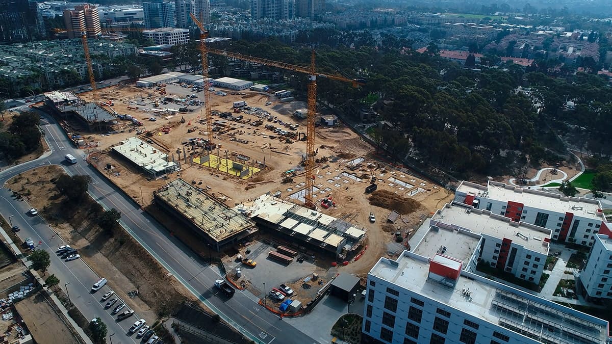Aerial view of a multifamily jobsite with cranes and adjacent residential towers