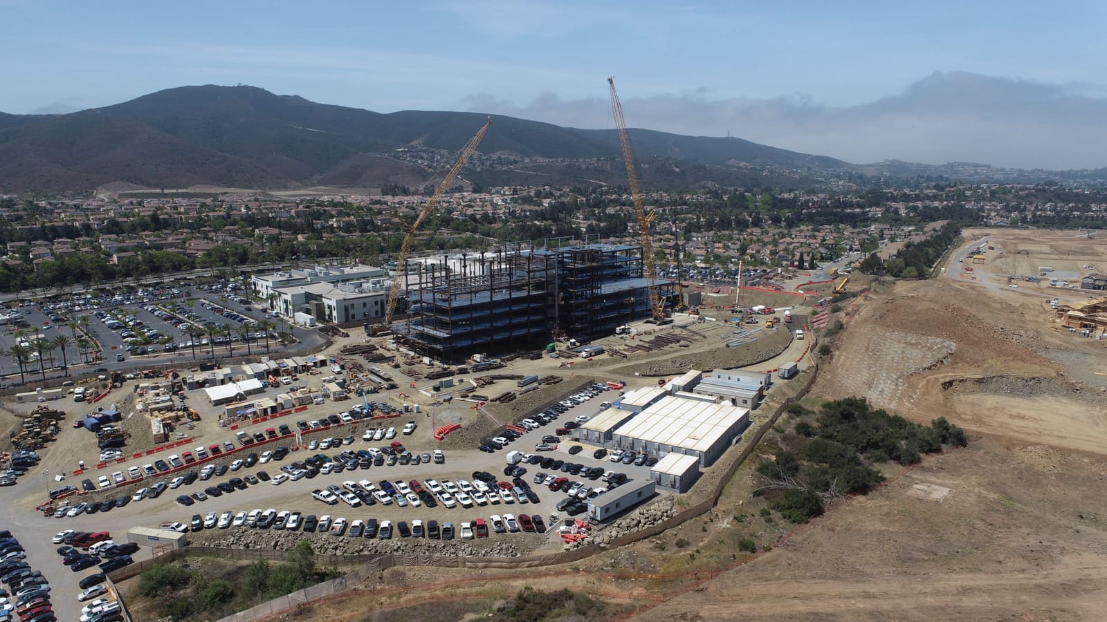 Aerial view of an active jobsite — towers under construction with cranes against the foothills
